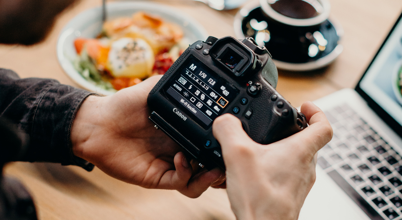 Person scrolling through menu screen on black DSLR camera